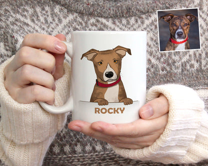 A person in a beige knit sweater holds a white ceramic mug featuring a cartoon illustration of a brown and white dog wearing a red collar, with the name 'ROCKY' printed below. A small reference photo of the real dog appears in the top right corner.