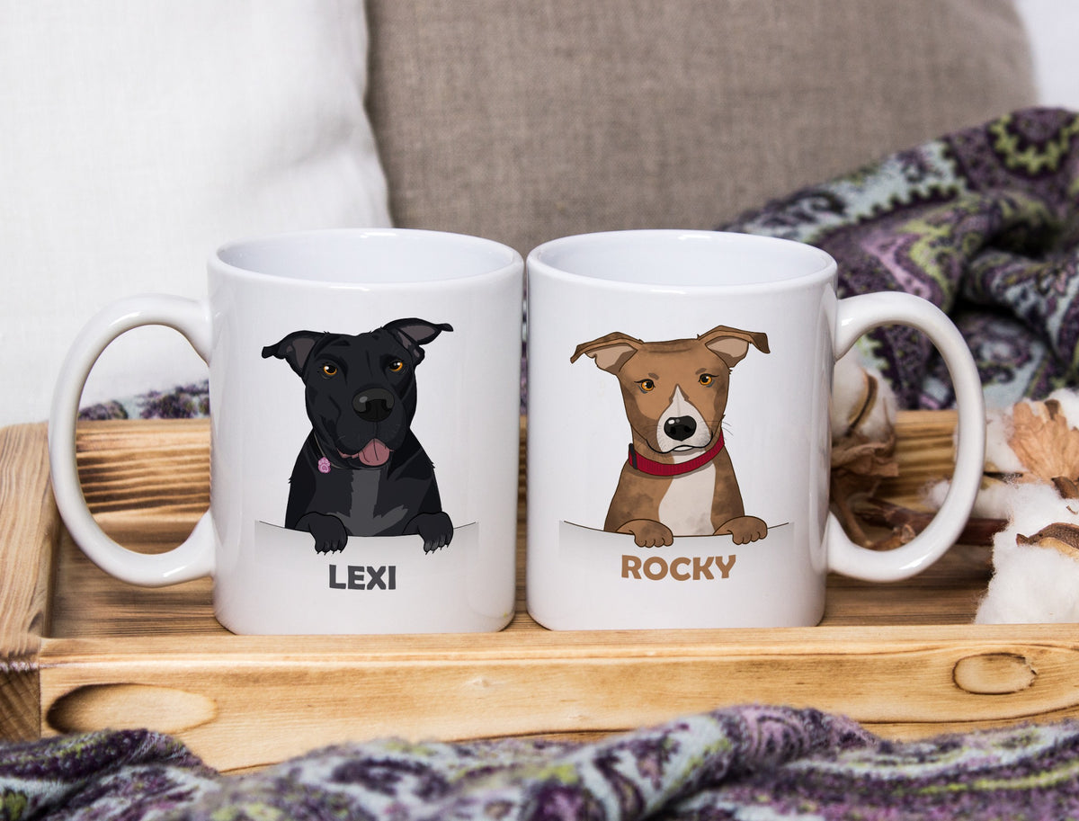 Two white ceramic mugs with custom dog illustrations, labeled 'LEXI' and 'ROCKY', displayed on a wooden tray with cozy home decor in the background.