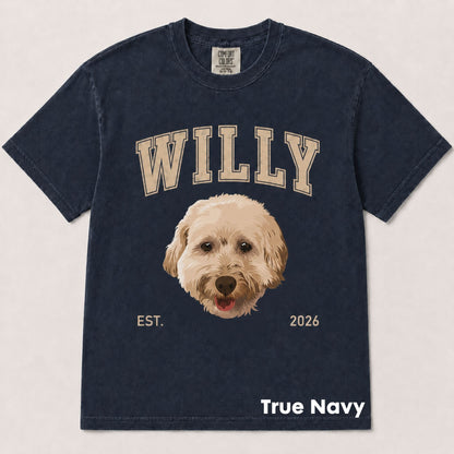 A navy blue short-sleeve t-shirt with a custom graphic print featuring the word 'WILLY' in beige varsity letters, a cartoon-style dog face in the center, and 'EST. 2026' below.