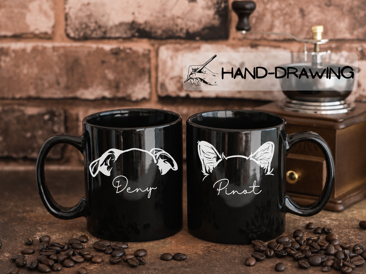 Two black ceramic coffee mugs with white graphic designs and the words 'Deny' and 'Pinat' displayed on a rustic wooden surface with coffee beans, a brick wall background, and a coffee grinder behind them. A 'HAND-DRAWING' watermark is visible.