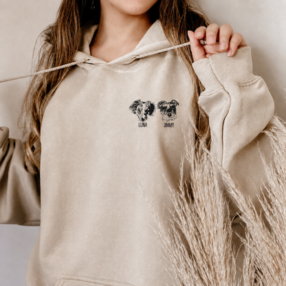 Woman wearing a cream hoodie with two black-and-white pet portraits labeled Luna and Jimmy