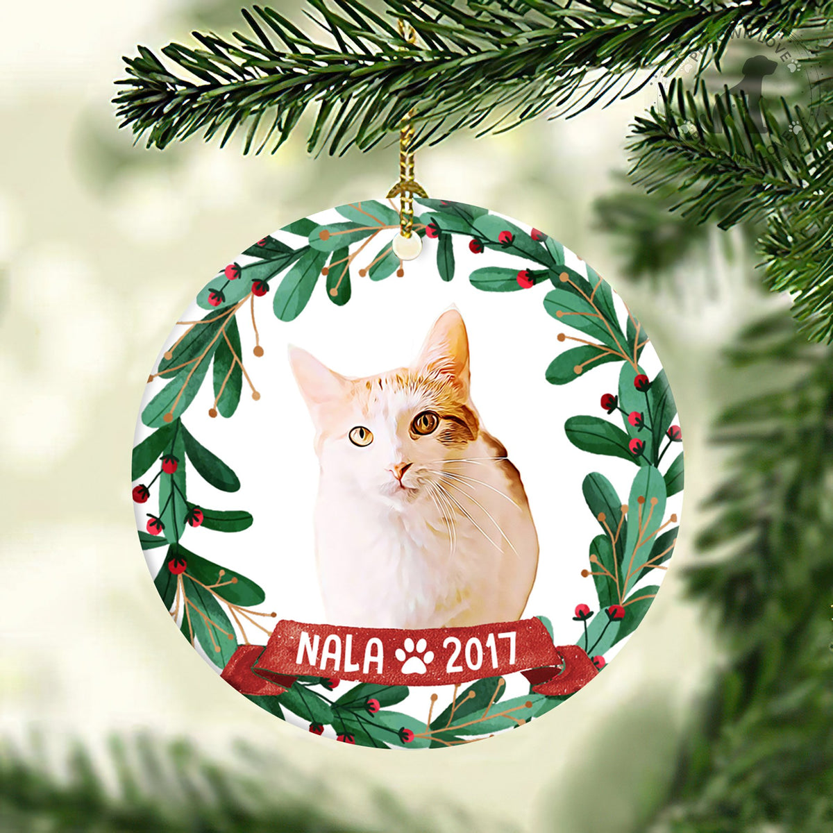 Personalized orange-and-white cat ornament hanging from an evergreen branch with name Nala