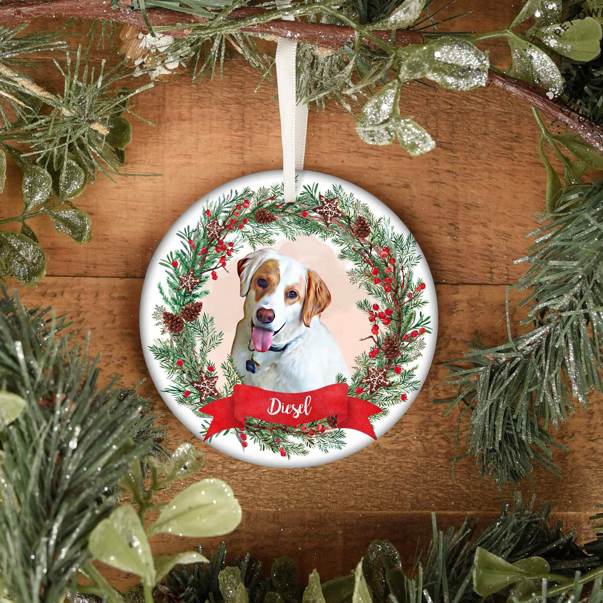 Round hanging pet ornament featuring a white and brown dog portrait, festive wreath, and Diesel name banner