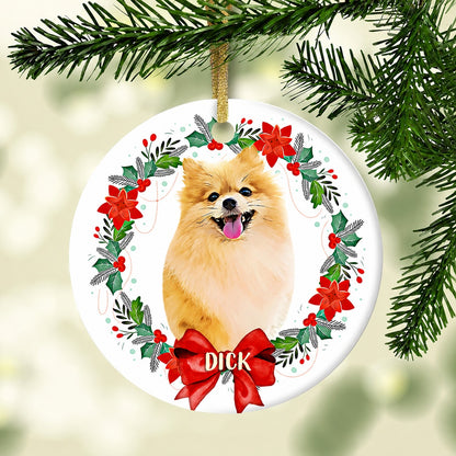Round pet ornament featuring a fluffy tan dog in a poinsettia and holly wreath