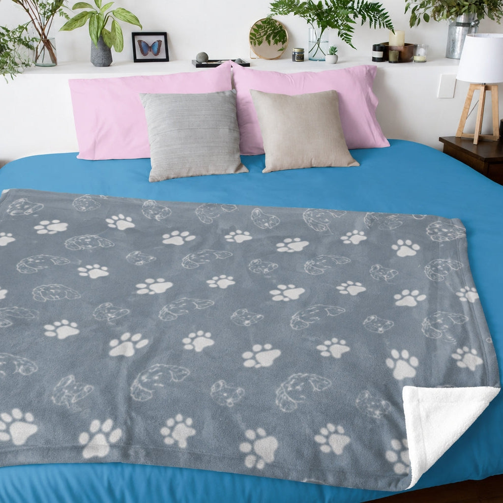 Gray pet blanket with varied outlined pet profiles and white paw prints draped over a bed