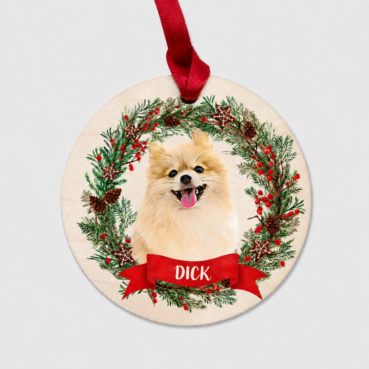 Round personalized pet ornament showing a fluffy tan dog in a pinecone and berry wreath with a red name ribbon