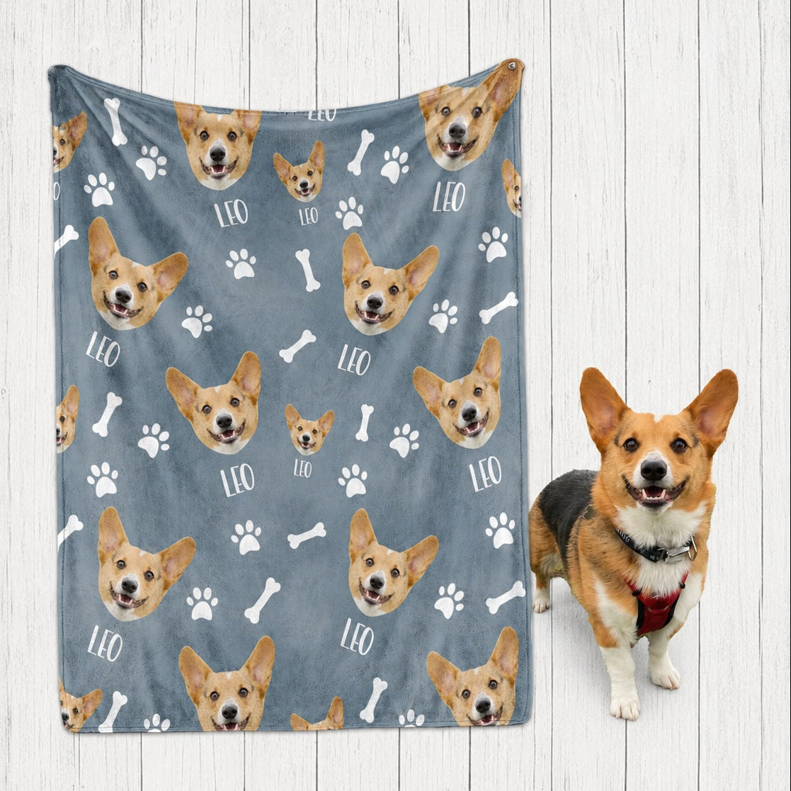 Blue personalized blanket featuring repeated corgi faces, the name Leo, paw prints, and bones beside a corgi