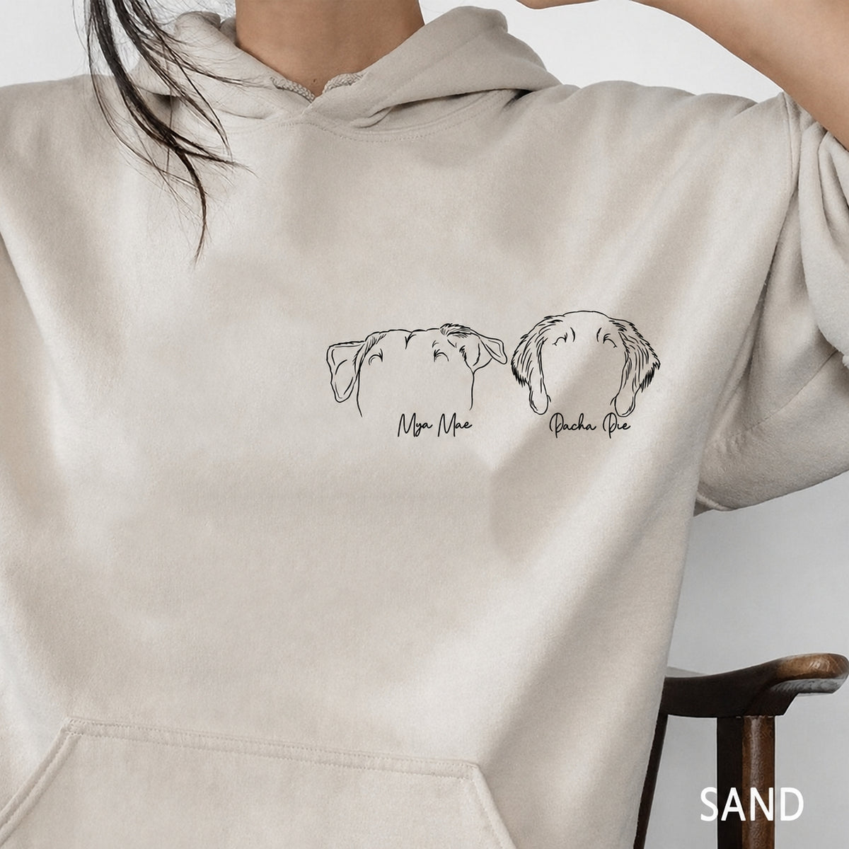 Sand hoodie close-up showing two minimalist pet outline portraits with names