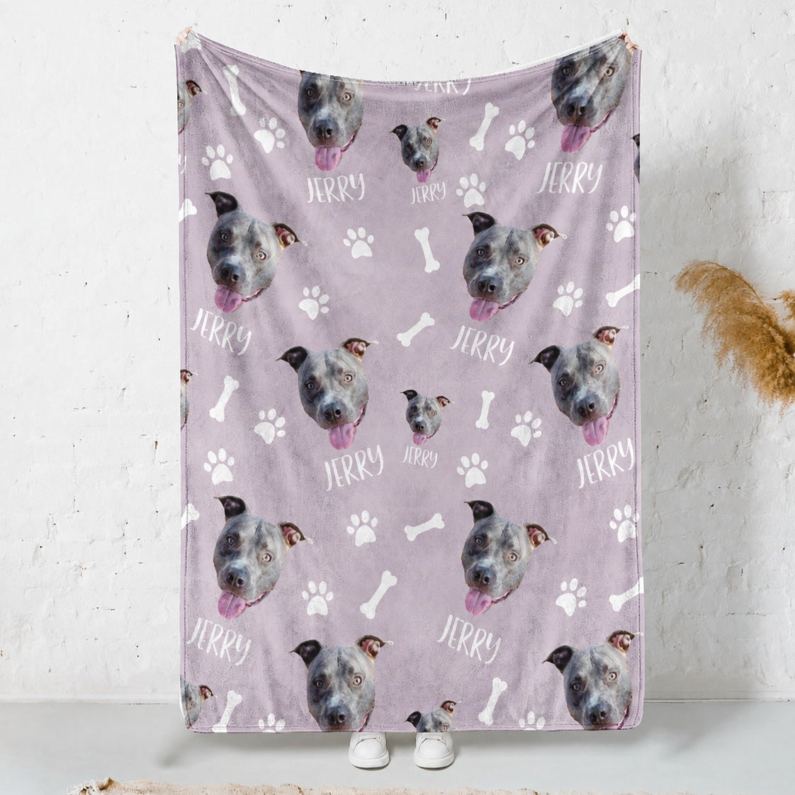 Personalized lavender blanket covered with repeated gray dog faces, the name Jerry, white paw prints, and bones