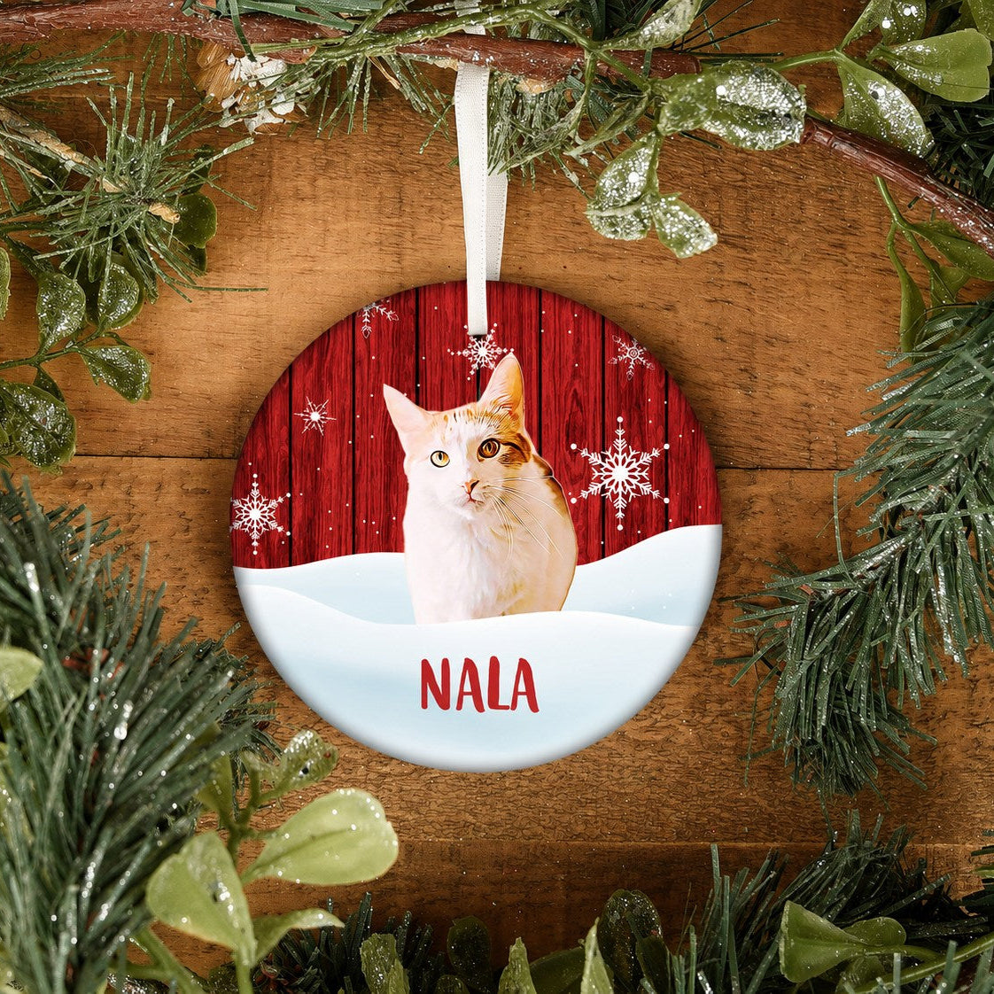 Round pet ornament with a white and orange cat portrait, red woodgrain snowflake background, and the name Nala