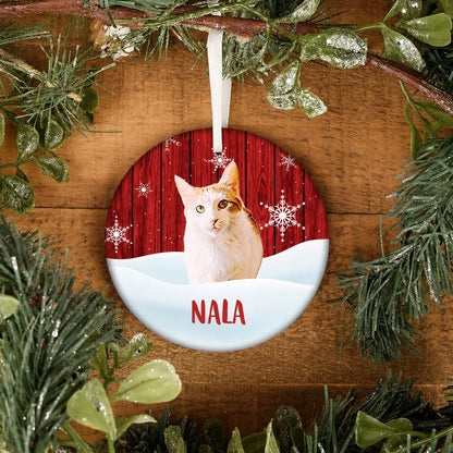 Round pet ornament with a white and orange cat portrait, red woodgrain snowflake background, and the name Nala