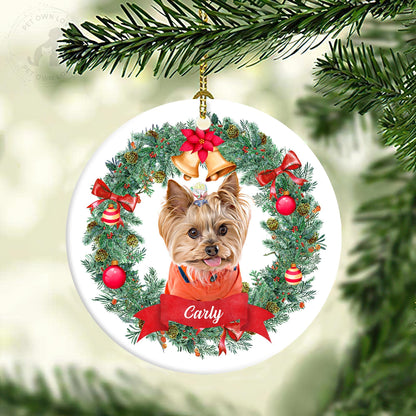 Round personalized pet ornament showing a small tan dog named Carly in a Christmas wreath