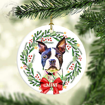 Personalized Boston Terrier ornament hanging from a tree branch in a leafy berry wreath with a red bow
