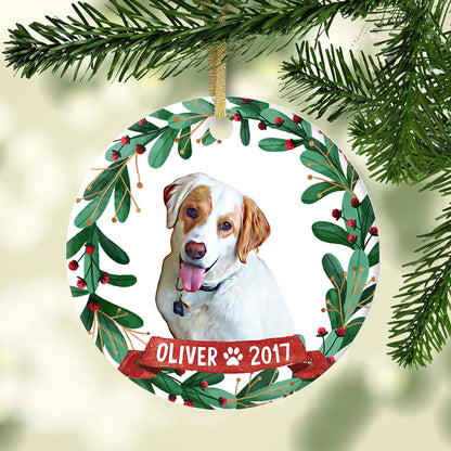 Custom dog portrait ornament hanging from an evergreen branch with name Oliver