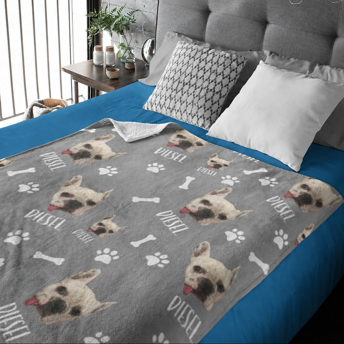 Gray personalized blanket with repeated small dog portraits, the name Dustin, paw prints, and bones on a bed