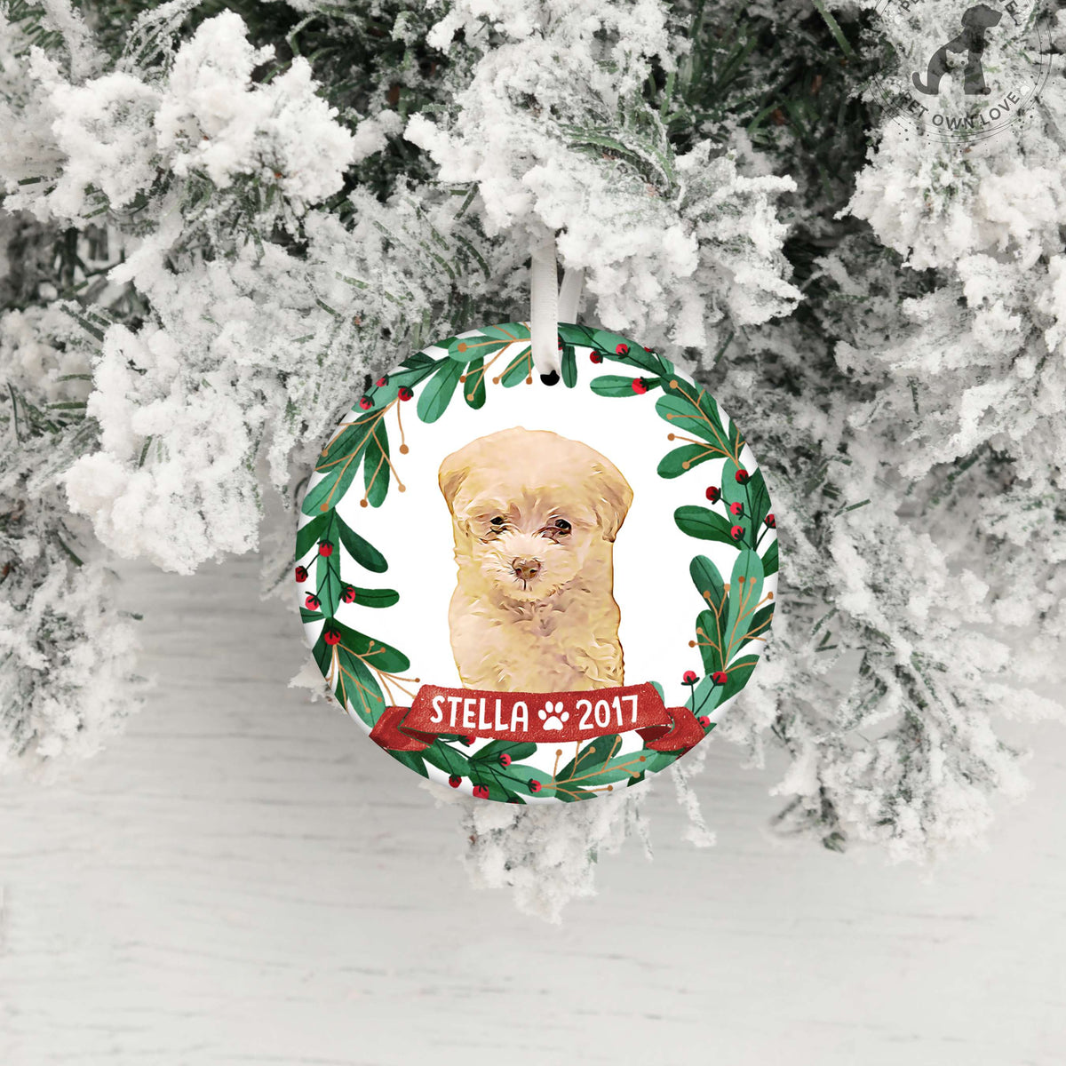 Personalized puppy ornament hanging against snowy branches with name Stella