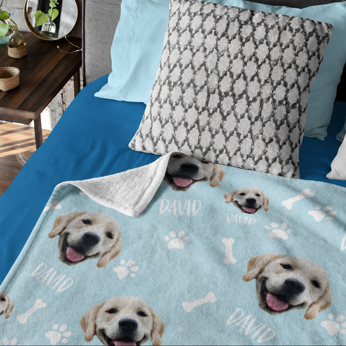 Light blue personalized blanket with repeated yellow Labrador puppy faces and the name David on a bed